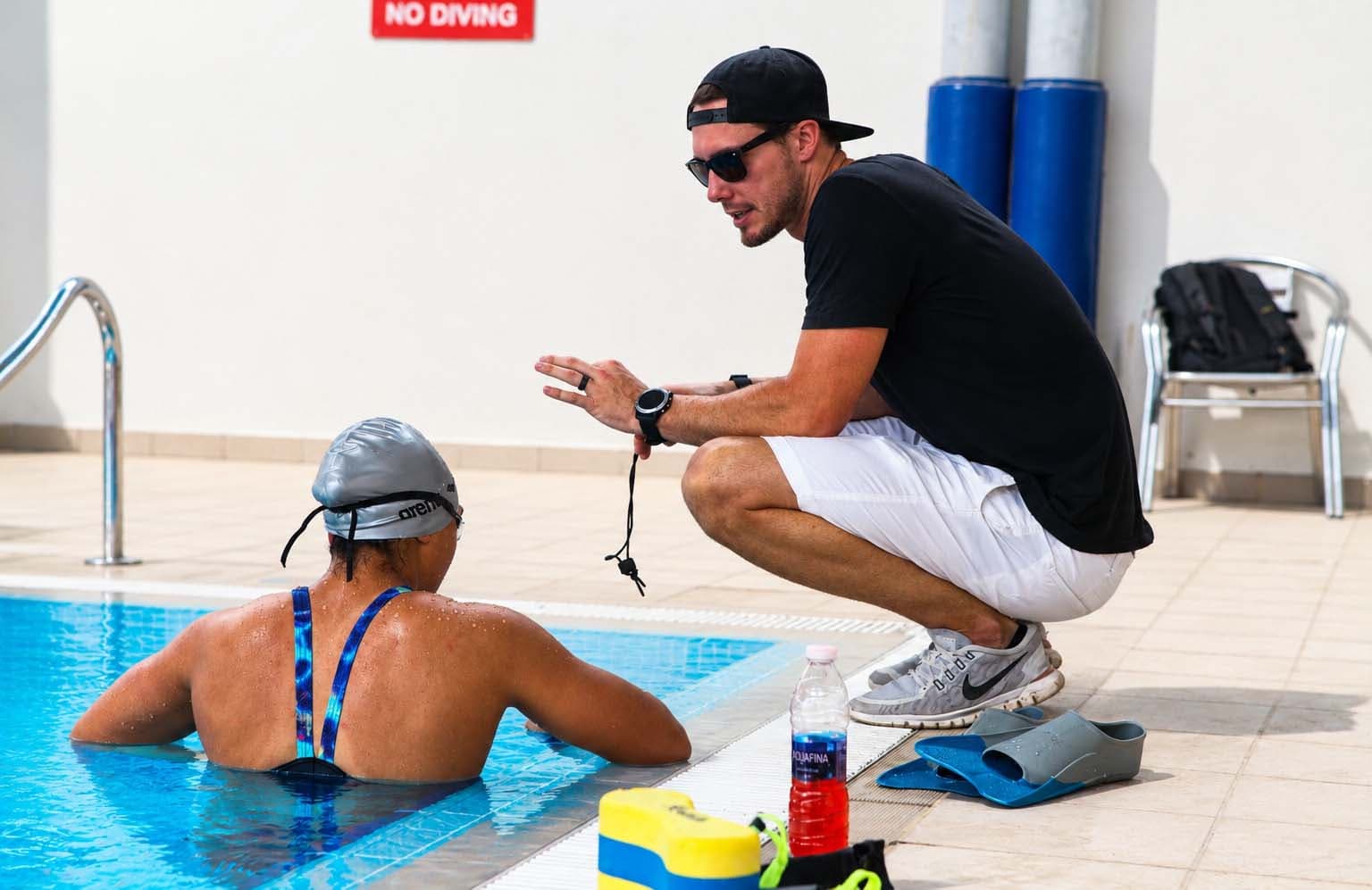 Coach on deck giving feedback to a swimmer during a private intensive session